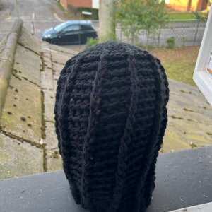 May include: Black knitted beanie with a cable knit pattern.