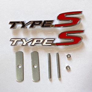 Puede incluir: Dos emblemas de coche cromados y rojos "TYPE S" con herrajes de montaje. Los emblemas tienen una base plateada con letras negras o blancas y un diseño de "S" rojo. Incluye dos placas metálicas, dos pernos y dos tuercas.