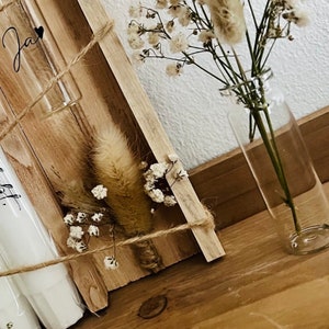 May include: A wooden box with two glass test tubes, one with a small bouquet of dried white flowers and a fluffy brown dried flower, and the other with a handwritten note. The box is tied with twine and the flowers are in a clear glass vase.