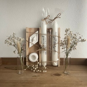 May include: A wooden box with two white candles, a small white boat, and two glass vases with dried flowers. The candles are wrapped in twine and have text that reads "Der sch&ouml;nste Weg" and "Alles Liebe - Gl&uuml;ckzeit".