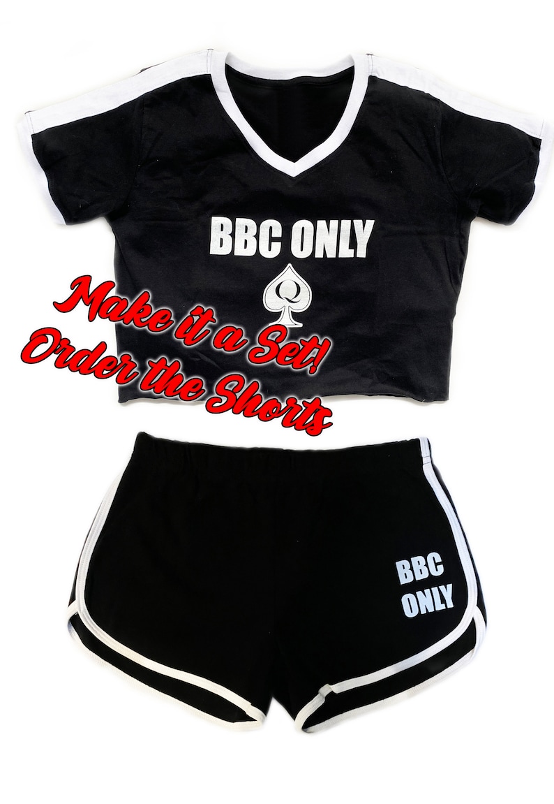 Pu&ograve; includere: Top corto nero e pantaloncini abbinati con bordini bianchi. Il top e i pantaloncini hanno il testo "BBC ONLY" e un simbolo di picche stampato su di essi. Il testo "Make it a Set! Order the Shorts" &egrave; scritto in rosso.