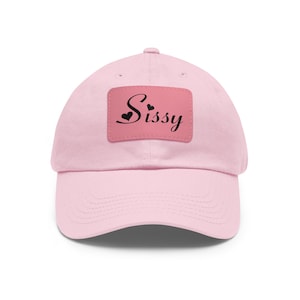 May include: Pink baseball cap with a pink patch that says "Sissy" in black cursive with two small black hearts above the word.