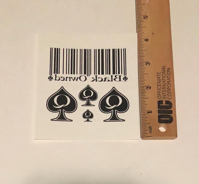 May include: Black Owned temporary tattoo with a barcode and four black queen of spades symbols.