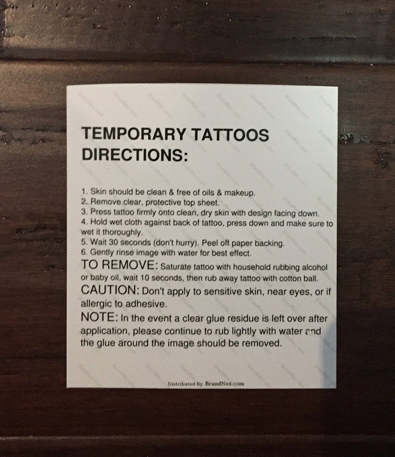 May include: A white rectangular card with instructions for applying temporary tattoos. The card includes directions for application and removal, along with a caution and a note. The text is in black, with the brand name at the bottom.