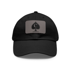May include: A black baseball cap with a gray patch featuring a black spade with a white 'C' inside.