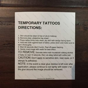 May include: White instructions for temporary tattoos. The instructions include how to apply and remove the tattoos, as well as a caution about applying the tattoos to sensitive skin, near eyes, or if allergic to adhesive.