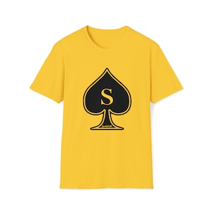 May include: A yellow t-shirt with a black spade design and the letter "S" in the center. The spade is outlined in black and the letter "S" is in yellow.
