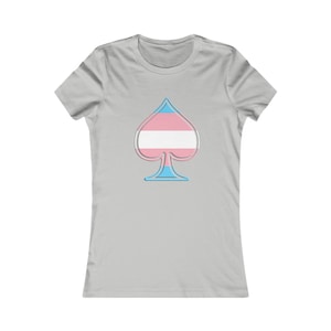 May include: A light gray women's t-shirt with a blue, white, and pink transgender pride flag design in the shape of a spade.
