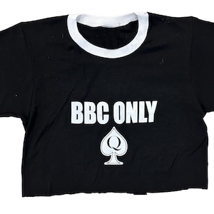 Pu&ograve; includere: Maglietta nera e bianca con collo a contrasto con il testo "BBC ONLY" e un'assegno bianco con una "Q" al suo interno.