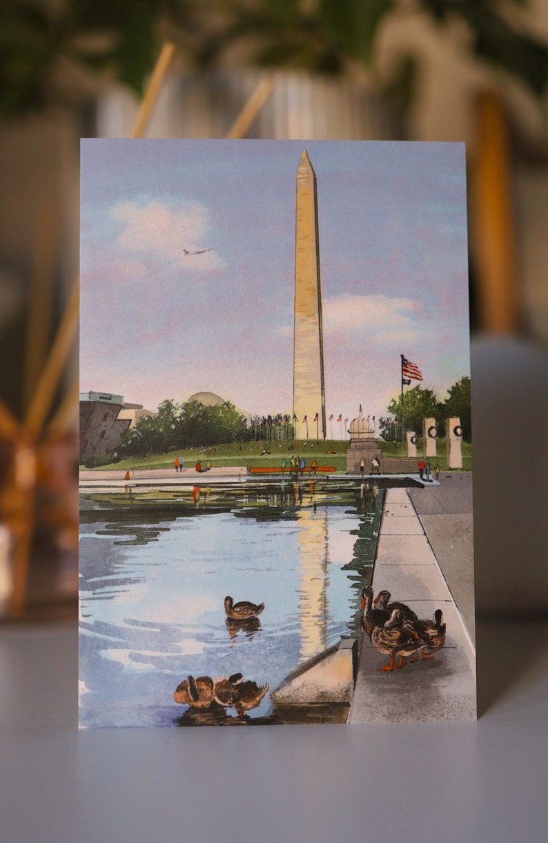 Hand-painted watercolor and pen illustration postcard of The Washington Monument in Washington, DC, featuring a charming duck family swimming in the Reflecting Pool. A whimsical and artistic postcard, perfect as a DC travel souvenir or gift for nature lovers.