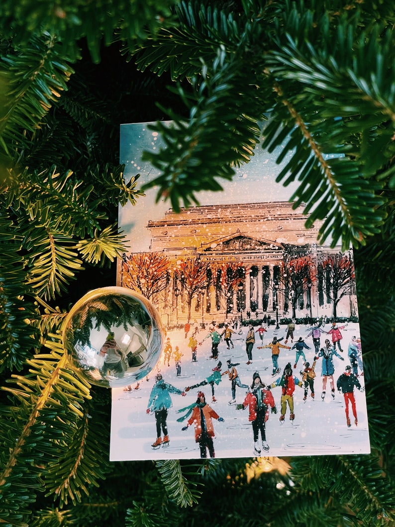 Washington DC Christmas postcard featuring a festive illustration of ice skaters at the National Gallery Sculpture Garden Ice Rink with snowy trees and holiday lights. Perfect DC holiday souvenir, Christmas greeting card, winter travel keepsake, or New Year postcard. Printed on luxe 4x6 matte cardstock, locally made in Washington DC & Virginia. Great for holiday decor lovers, DC travelers, and postcard collectors.