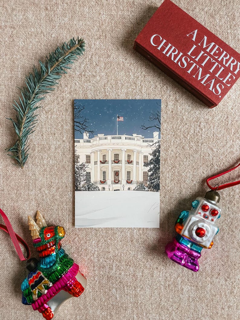 Washington DC Christmas postcard featuring a festive gouache illustration of the White House covered in snow and decorated for the holidays. A perfect DC winter souvenir, holiday greeting card, or collectible art print for Christmas decor lovers, Washington DC travelers, White House history buffs, and postcard collectors. Printed on premium 4x6 matte cardstock with high-resolution festive artwork. Designed and made in the USA.