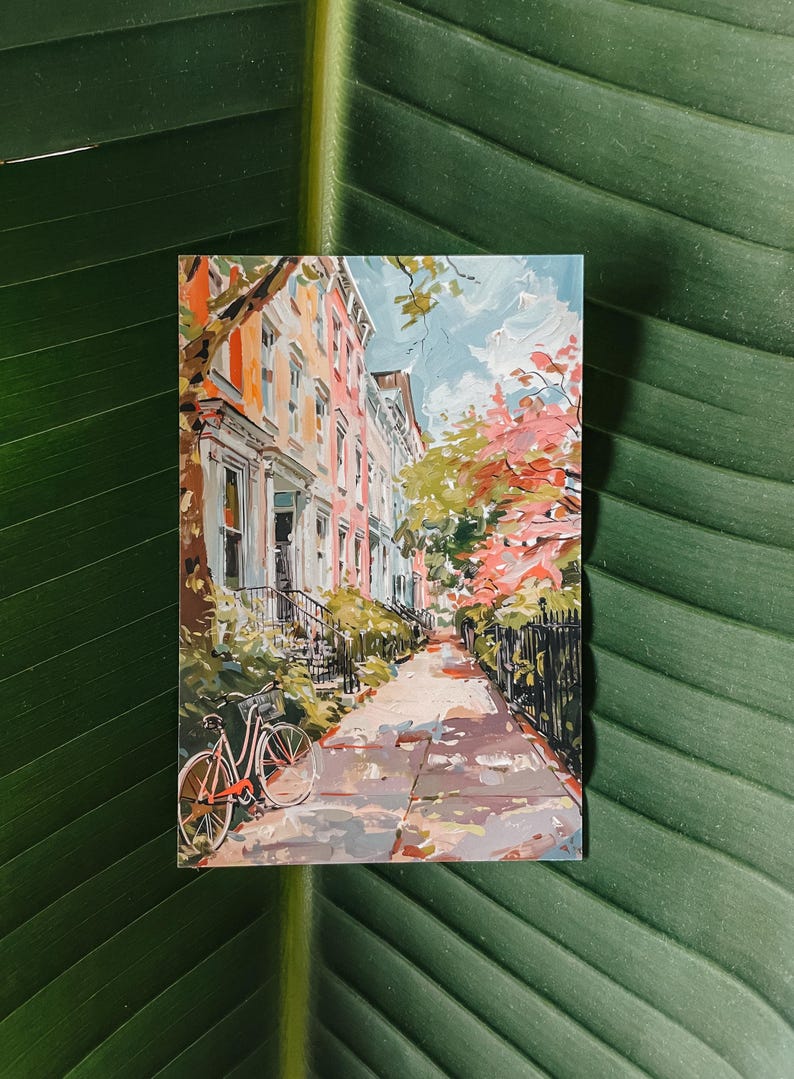 Illustrated postcard of a summer day in Georgetown, Washington, DC, featuring bicycles, colorful row houses, and lush greenery. Printed on a 4x6" matte cardstock, perfect for mailing or collecting.