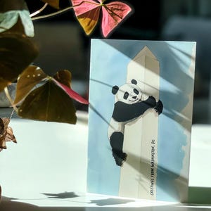 Washington DC postcard featuring a whimsical illustration of a giant panda climbing The Washington Monument. A fun and charming souvenir celebrating the return of pandas to DC. Perfect gift for panda lovers, Washingtonians and Washington, DC enthusiasts!