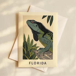 May include: A postcard with a vintage illustration of an iguana. The iguana is rendered in green and black, with a red eye, and is perched on a branch. The word "FLORIDA" is printed in bold, black letters at the bottom of the card.