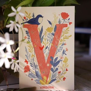 Virginia postcard featuring the letter "V" decorated with delicate floral patterns and charming birds. A 4x6" nature-inspired Virginia souvenir, printed on premium matte cardstock, celebrating the state's natural beauty and wildlife.