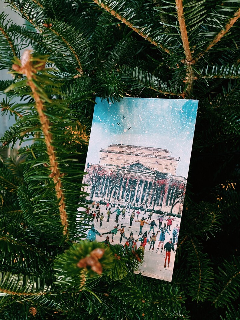 Washington DC Christmas postcard featuring a festive illustration of ice skaters at the National Gallery Sculpture Garden Ice Rink with snowy trees and holiday lights. Perfect DC holiday souvenir, Christmas greeting card, winter travel keepsake, or New Year postcard. Printed on luxe 4x6 matte cardstock, locally made in Washington DC & Virginia. Great for holiday decor lovers, DC travelers, and postcard collectors.