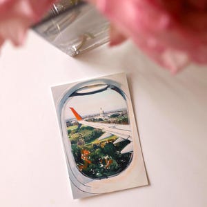 Hand-drawn Washington DC postcard featuring watercolor and ink illustration with the US Capitol Building seen from the airplane window. Elegant 4x6 postcard with watercolor-style artwork, perfect for Washington DC tourists, DC locals, collectors, post crossers, and travel souvenirs collectors.