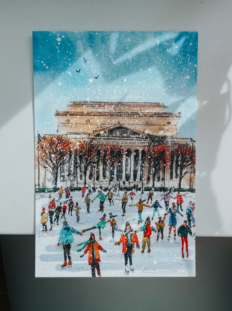Washington DC Christmas postcard featuring a festive illustration of ice skaters at the National Gallery Sculpture Garden Ice Rink with snowy trees and holiday lights. Perfect DC holiday souvenir, Christmas greeting card, winter travel keepsake, or New Year postcard. Printed on luxe 4x6 matte cardstock, locally made in Washington DC & Virginia. Great for holiday decor lovers, DC travelers, and postcard collectors.
