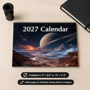 May include: A 2027 calendar with a spiral binding featuring a space-themed cover with a large ringed planet, rocky terrain, and a glowing horizon. The text reads 2027 Calendar. It is available in 11 inches by 8.5 inches or 14 inches by 11.5 inches.