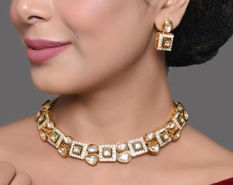May include: A gold necklace and earrings set with white stones and green accents. The necklace features a geometric design with square and teardrop shapes.