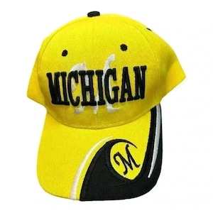 May include: A bright yellow baseball cap featuring the word MICHIGAN embroidered in bold black letters across the front. The curved brim includes a black accent panel with a white curved line and a black embroidered letter M inside a circle.
