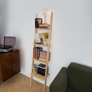 以下が含まれることがあります： 黒い持ち手と「But First, Coffee」のテキストが太字の黒でプリントされた白いセラミックマグ。マグカップはニュートラルな背景に置かれ、シンプルなデザインが際立っています。