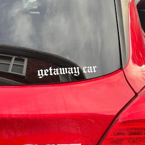 May include: A red car with a white sticker that says "getaway car" in a gothic font.