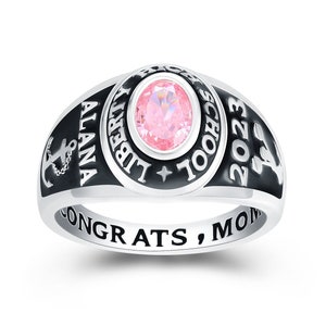 May include: A silver class ring with a black band and a pink stone. The ring says "Liberty School" and "2023" on the top and "Alana Congrats, Mom" on the bottom.