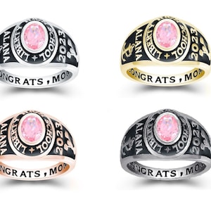May include: Four different colored class rings with a pink stone. The rings are engraved with "ALANA", "LIBERTY SCHOOL", "2023", and "CONGRATS, MOM".