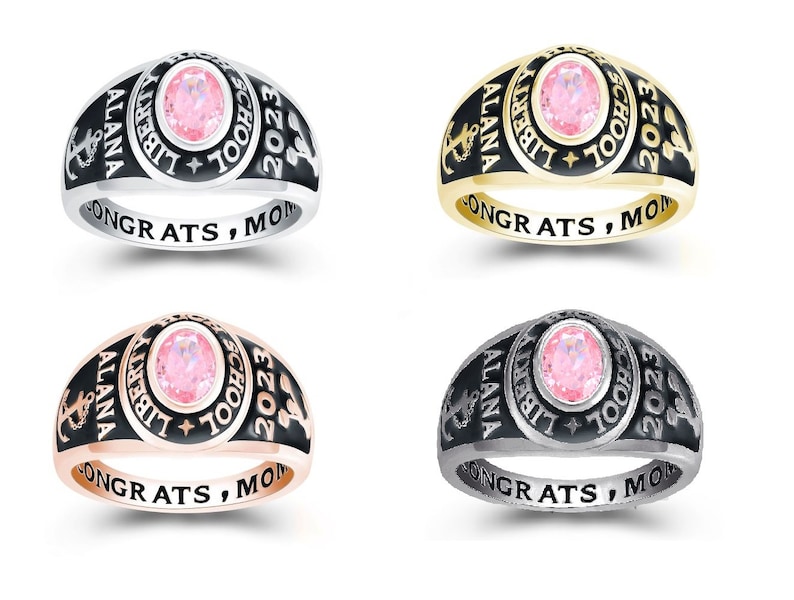 May include: Four different colored class rings with a pink stone. The rings are engraved with "ALANA", "LIBERTY SCHOOL", "2023", and "CONGRATS, MOM".