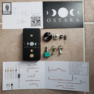 Könnte beinhalten: Ein schwarzes Pedal mit dem Wort "OSTARA" darauf gedruckt. Das Pedal hat drei Knöpfe und einen Schalter. Das Pedal ist von verschiedenen elektronischen Komponenten umgeben, darunter Widerstände, Kondensatoren und Drähte. Das Bild zeigt auch ein Diagramm der Platine des Pedals.
