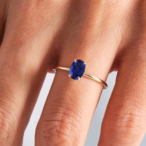Puede incluir: Un anillo de oro con una piedra preciosa ovalada azul.
