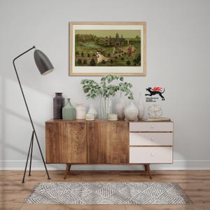 May include: A wooden sideboard with a dark brown cabinet door and three white drawers, topped with several vases, candles, and a framed landscape painting. A black floor lamp stands to the left, and a geometric rug lies on the floor.