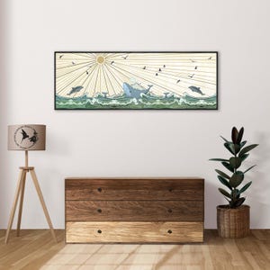 Può includere: Un'illustrazione incorniciata di una balena che salta fuori dall'acqua con un sole che splende sopra. La balena è blu e l'acqua è verde. Ci sono uccelli che volano nel cielo sopra la balena.