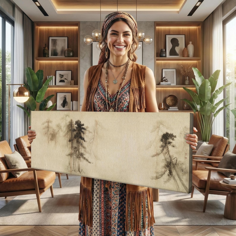 K&ouml;nnte beinhalten: Eine Frau h&auml;lt eine rechteckige Leinwand mit einer minimalistischen Tuschemalerei von B&auml;umen. Das Kunstwerk weist eine neutrale Farbpalette mit Schwarz- und Graut&ouml;nen auf. Die Frau tr&auml;gt eine braune Weste mit Fransen, ein gemustertes Kleid und Schmuck.
