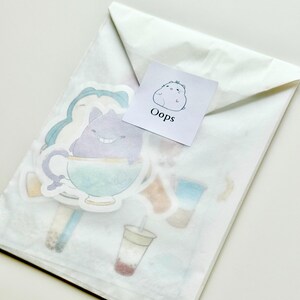 May include: A white envelope with a sticker on it. The sticker has a cartoon character on it and the word "Oops" written below it. The envelope contains several other stickers with cartoon characters and designs.