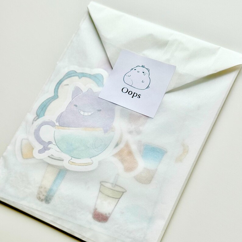May include: A white envelope with a sticker on it. The sticker has a cartoon character on it and the word "Oops" written below it. The envelope contains several other stickers with cartoon characters and designs.