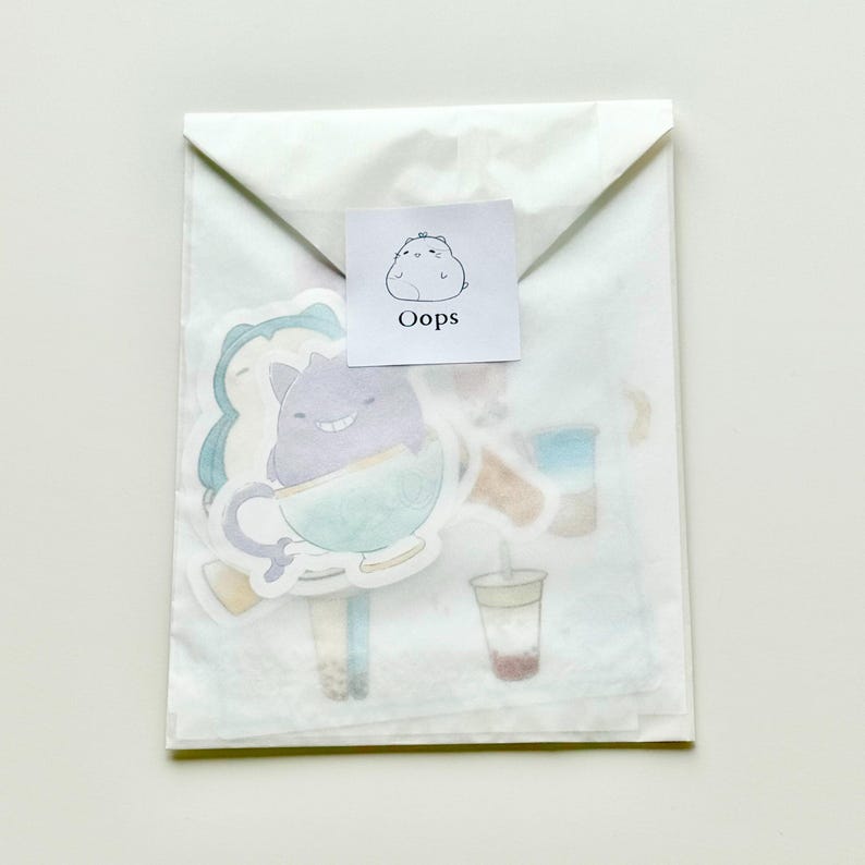 May include: A white paper envelope with a sticker on the front that says "Oops". The sticker features a cartoon character. Inside the envelope are several stickers with cartoon characters and illustrations of drinks.