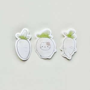 May include: Three white radish stickers with green tops. One radish has a cat face drawn on it.