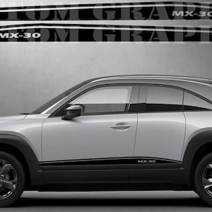 Puede incluir: Un SUV Mazda MX-30 plateado con detalles laterales negros y el texto "MX-30" en el lateral. El coche se muestra en vista de perfil.