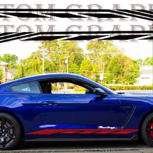 Puede incluir: Un Ford Mustang azul con rayas de carreras negras y rojas. El coche tiene la palabra "Mustang" escrita en el lateral en rojo.