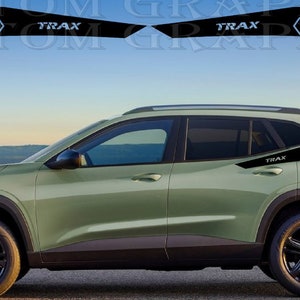Könnte beinhalten: Ein grüner Chevrolet Trax SUV mit schwarzen Akzenten und einer Wabengrafik an der Seite. Das Auto hat schwarze Räder und einen schwarzen Dachträger.