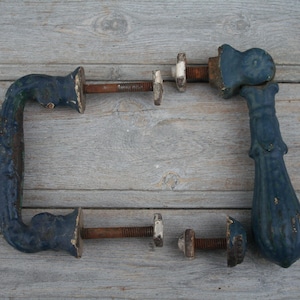 May include: A pair of antique door handles made of cast iron. The handles are painted a dark blue colour and have a decorative design. The handles are connected by a metal rod.