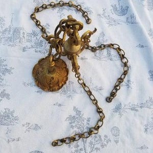 Peut inclure: Un lustre en métal doré avec une chaîne décorative et une base ronde ornée.