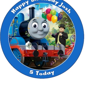 Puede incluir: Imagen circular con borde azul que presenta a Thomas el Tren. La imagen incluye el texto "Happy Birthday Josh" y "5 Today", junto con globos y un hombre con traje. Tema de cumpleaños.