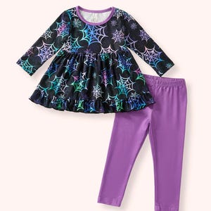 May include: A two-piece outfit featuring a long-sleeved black top with a spiderweb pattern in shades of blue, green, and purple, paired with solid purple leggings. The top has a ruffled hem and a purple neckline.