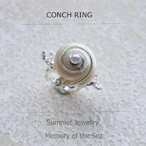 May include: A silver-toned conch ring featuring a spiral seashell design with a central pearl. The image includes the text "Conch Ring", "Summer Jewellery", and "Memory of the Sea".