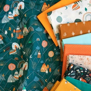 Puede incluir: Una colección de cuadrados de tela con una variedad de patrones, que incluyen montañas, árboles, arcoíris y animales. Las telas son en tonos de verde azulado, naranja, marrón, blanco y azul.