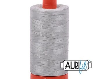 May include: A spool of silver gray thread with an orange plastic bobbin and the word "Aurifil" printed on a blue label.